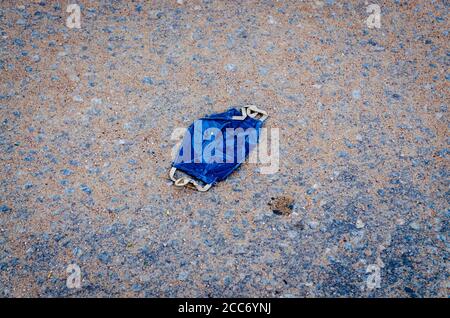 Isolierte blaue hausgemachte Schutzmaske auf die Straße geworfen. Stockfoto