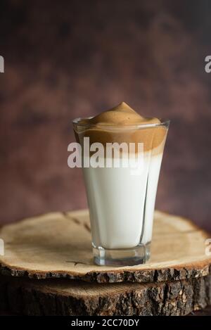 Dalgona kalter Kaffee mit Milch und Schaum, auf einem geschnittenen Holzbrett, Instant-Kaffee, koreanische Trend hausgemachten Kaffee Rezept Stockfoto
