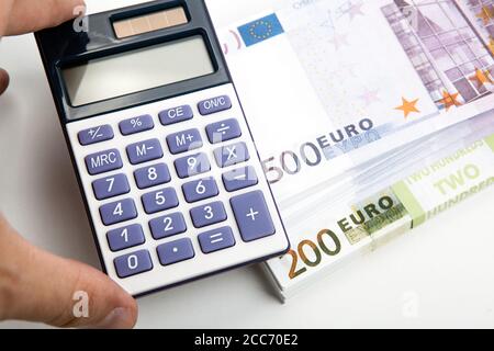 Taschenrechner in der Hand und ein Bündel von Banknoten 500 Und 200 Euro Stockfoto