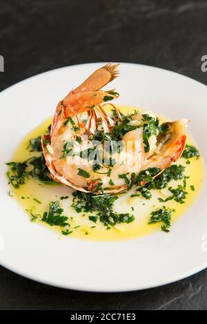 Ein halber Hummerschwanz, Homarus gammarus, der mit einer Butter, Knoblauch und Petersilie Sauce gegrillt und beträufelt wurde. Der Hummer wurde im Engli gefangen Stockfoto