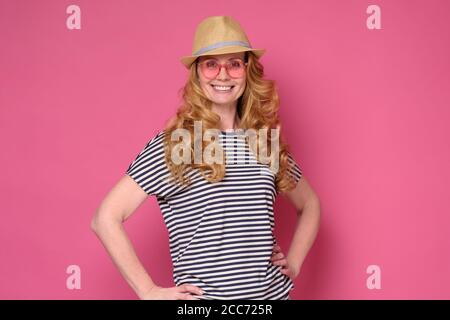 Schöne reife Frau tragen Sonnenbrille und Hut lächelnd. Stockfoto