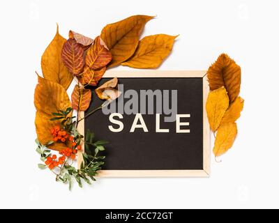 Herbstverkauf: Tafel mit Wort Verkauf in Holzbuchstaben eingerahmt mit gelben Herbstblättern und Ebereschen Ästen und Beeren auf weißem Hintergrund. Saisonal s Stockfoto