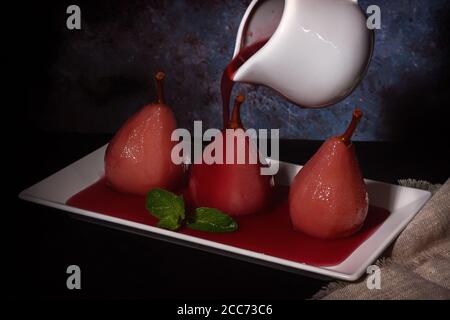 Pochierte Birnen in Rotwein mit Zimt und Anis. Stockfoto