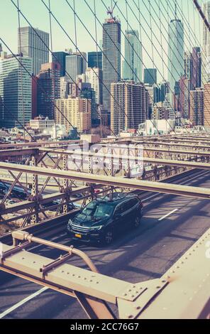 Ein Auto, das mit der Skyline von Manhattan über die Brooklyn Bridge fährt Im Hintergrund Stockfoto