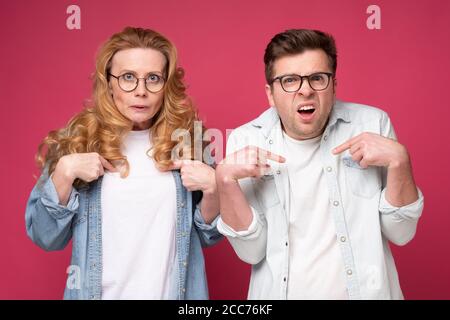 Mann und Frau zeigen mit den Fingern auf sich selbst und haben zweifelhaften Gesichtsausdruck Stockfoto