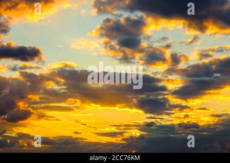 Ein sehr dramatischer Himmel voller Gelb, Blau und Orangen. Kontrastierende Wolken während des Sonnenuntergangs von der untergehenden Sonne beleuchtet. Hell gesättigt natürlich Stockfoto