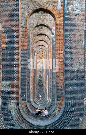 Junge Leute unter dem Ouse Valley Viaduct (Balcombe Viaduct) mit der London to Brighton Railway Line über den River Ouse in Sussex, Großbritannien Stockfoto