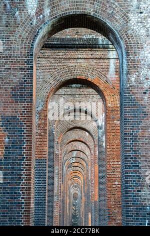 Blick durch die Bögen des Ouse Valley Viadukts (Balcombe Viaduct), das die London-Brighton-Eisenbahnlinie über den Fluss Ouse in Sussex, Großbritannien, transportiert Stockfoto