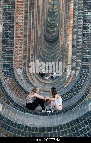 Junge Leute unter dem Ouse Valley Viaduct (Balcombe Viaduct) mit der London to Brighton Railway Line über den River Ouse in Sussex, Großbritannien Stockfoto