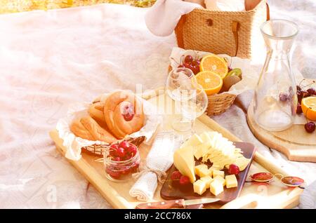 Romantisches Picknick im Park auf dem Rasen. Käse, Obst, Brot, Saft und Snacks auf der Decke Stockfoto