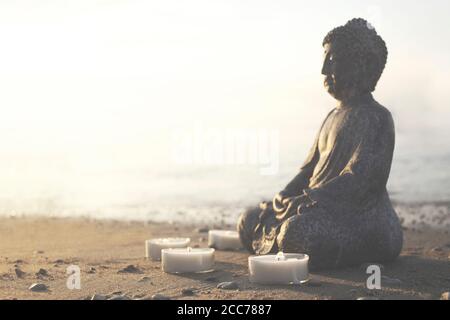 buddha-Statue mit brennenden Kerzen mit Blick auf den Ozean Stockfoto