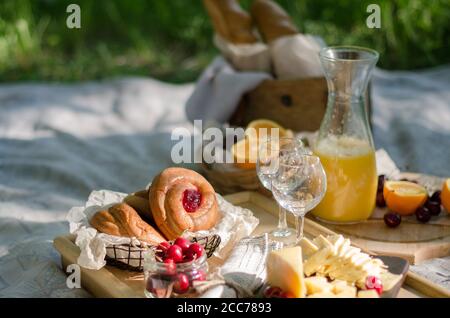 Romantisches Picknick im Park auf dem Rasen. Käse, Obst, Brot, Saft und Snacks auf der Decke Stockfoto