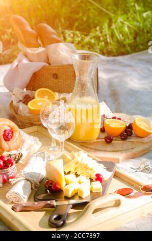 Romantisches Picknick im Park auf dem Rasen. Käse, Obst, Brot, Saft und Snacks auf der Decke Stockfoto