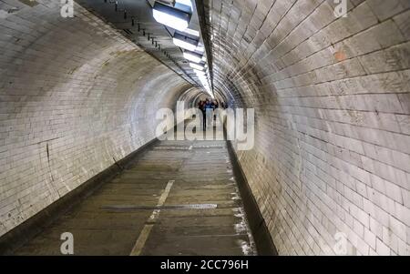 Weitwinkelfoto des Greenwich-Fußtunnels unter der Themse in London, verschwommene Fußgänger in der Ferne Stockfoto