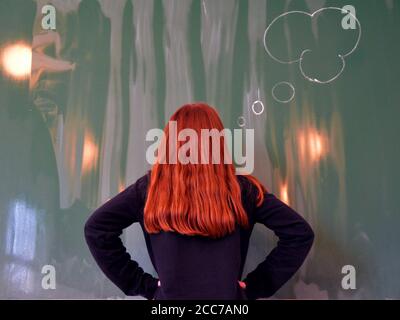 Redhead Schulmädchen steht vor dem Brett und Denken...Konzept Zum Hinzufügen von Text Stockfoto