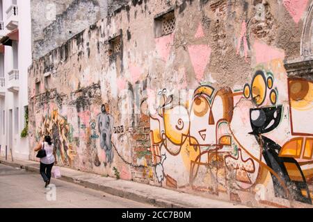 Eine einheimische Frau schlendert an einer großen Wand mit Graffiti vorbei Kunst in Cartagena Stockfoto