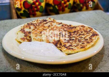 Zucchini-Pfannkuchen mit Sauce aus saurer Sahne Stockfoto