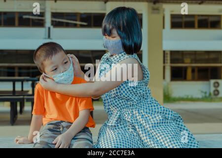 Zwei Kinder tragen Masse, um sich vor dem Coronavirus zu schützen. Stockfoto