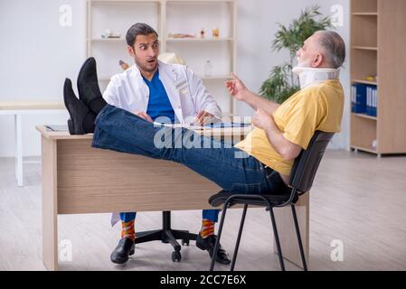 Alter Hals verletzten Mann besucht jungen Arzt Stockfoto
