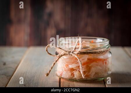 Hausgemachtes Sauerkraut auf dunkelbraunem Hintergrund. Fermentierter Kohl in einem Glas auf einem hölzernen Hintergrund. Öko-Lebensmittel, der Trend zu gesunder Ernährung. Platz für yo Stockfoto