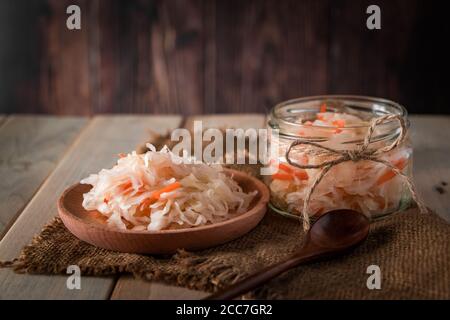 Hausgemachtes Sauerkraut auf dunkelbraunem Hintergrund. Fermentierter Kohl in einem Glas auf einem hölzernen Hintergrund. Öko-Lebensmittel, der Trend zu gesunder Ernährung. Platz für yo Stockfoto