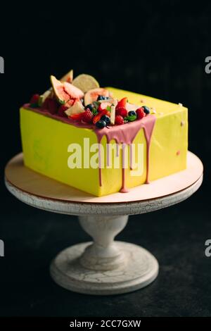 Gelbe Zitrusfrüchte Kuchen dekoriert mit Feigen, Himbeeren, Heidelbeeren und Zitrone. Stockfoto