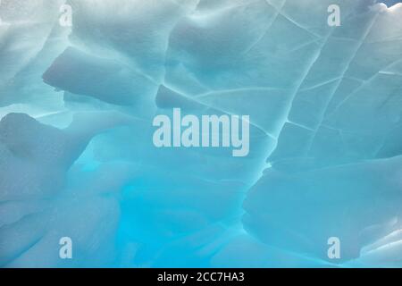 Nahaufnahme eines hinterleuchteten Eisbergs, mit einer Reihe von blauen Farbtönen und interessanten Formen und Mustern, die entlang der Küste der Antarktis schweben. Stockfoto