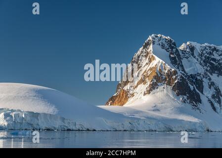 Gletscher und Berge an einem klaren und sonnigen Nachmittag im Lemaire Channel in der Antarktis. Stockfoto