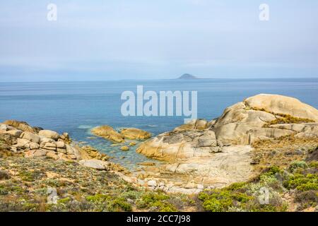 Granitfelsen entlang der Küste von Trousers Point, Flinders Island, Furneaux Group, Tasmanien, mit Mount Chappell Island in der Ferne Stockfoto