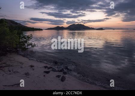 Der Himmel spiegelte sich am späten Abend im Meer, als Dunkelheit im Komodo Nationalpark, Indonesien, fällt. Stockfoto