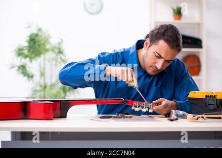 Junger Mann Reparatur der Gitarre Stockfoto