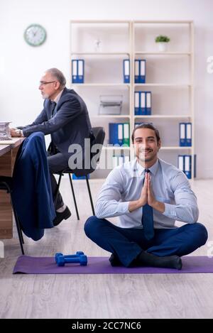 Zwei Mitarbeiter, die am Arbeitsplatz körperliche Übungen machen Stockfoto