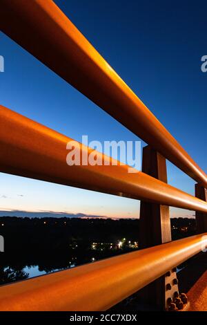 Absract Blick durch robuste Metallgeländer; Blick auf den Sonnenuntergang und Vorstadt Skyline von hinter schützenden Metallschiene Guard Stockfoto