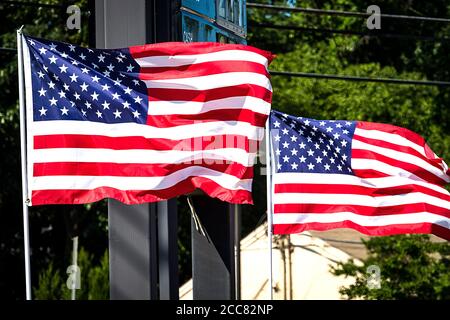 Zwei amerikanische Flaggen winken lautstark im Wind in einem Vorort Stockfoto