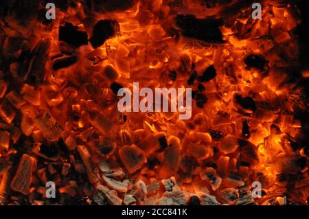 Rot flammende Textur mit schwelender Glut von Feuerholz und lodernden Flammen. Bonfire Textur in der Dunkelheit Stockfoto