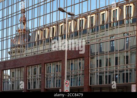 Hamburg / Deutschland - 09 05 2018: Verzerrte Spiegelung des historischen Gebäudes mit Kapellenturm in Glaswand reflektierende Oberfläche des modernen Gebäudes. Kont Stockfoto