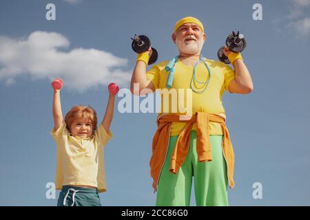 Sportübungen für Kinder. Hanteln anheben. Portrait von älteren Mann und niedlichen Kind Hanteln heben. Großvater und Sohn machen Übungen. Stockfoto