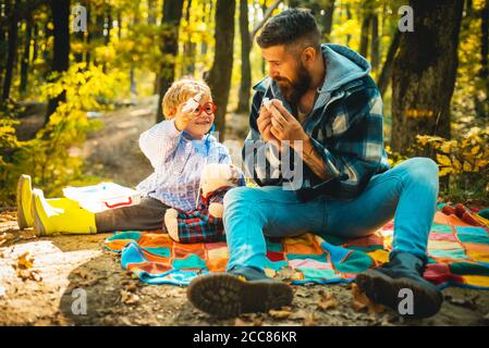 Kind macht eine Heilung für die gemeinsame Kälte im Herbst Park. Vater und Sohn spielen im Herbstwald. Vater und Sohn im Herbstpark spielen lachend. Stockfoto