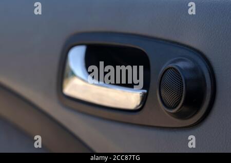 Verchromter Innentürgriff mit Lautsprecher. Nahaufnahme eines sauberen Fahrzeuginnenraums. Waschkonzept und Reinigungskonzept. Selektiver Fokus. Stockfoto
