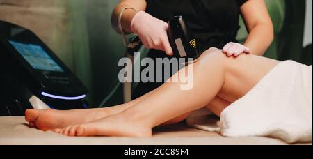 Seitenansicht Foto einer kaukasischen Frau mit einem Laser Haarentfernung am Bein im Spa-Center mit Neues Gerät mit Bildschirm Stockfoto