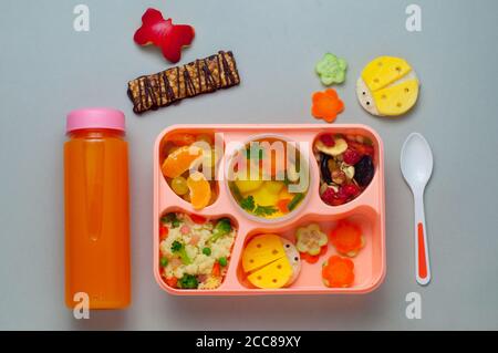 Lunchbox mit Obst, Suppe, Couscous-Salat und lustigen Sandwiches auf grauem Hintergrund Stockfoto