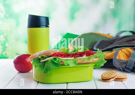 Lunchbox mit Sandwich in der Nähe von Keksen, Thermoskanne und Schulrucksack Stockfoto