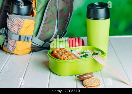 Lunchbox mit Reis und Sandwich in der Nähe von Schulrucksack Stockfoto