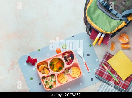 Lunchbox mit Gemüsesuppe, Couscous-Salat und lustige Sandwiches in der Nähe von Rucksack Stockfoto