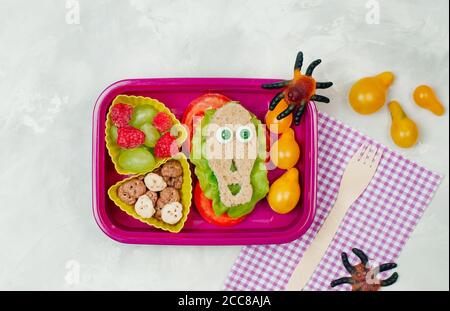 Offene Halloween-Lunchbox mit Schulessen in Totenkopf-Form Sandwich auf grauem Beton Hintergrund Stockfoto