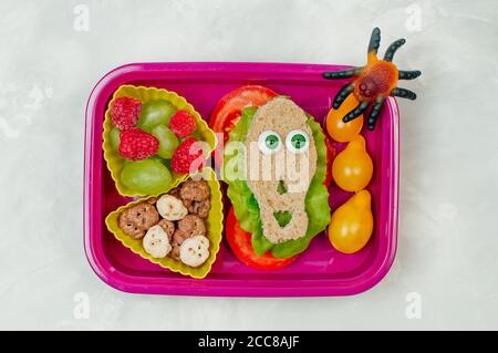 Offene Halloween Lunchbox mit Totenkopf-Sandwich auf grau Hintergrund Stockfoto