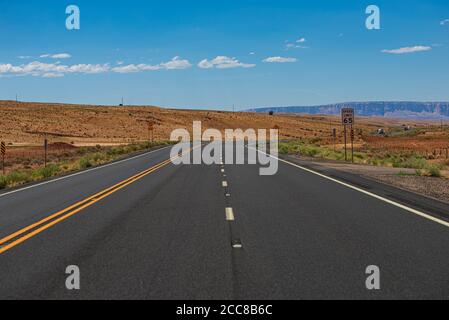 Wüstenautobahn bei Sonnenuntergang, Reisekonzept, USA. Asphalt Autobahn Straße und Himmel Sonnenuntergang Wolken Landschaft. Roadtrip nach Amerika. Stockfoto