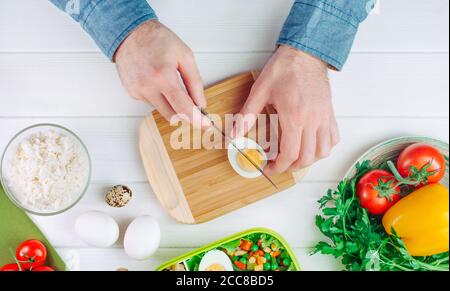 Nahaufnahme von oben Ansicht der Männer Hände Schneiden Ei für Lunchbox Stockfoto