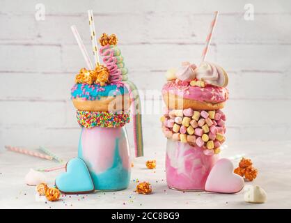 Zwei Freak-Shakes mit Donut, Marshmallow, Popcorn und Marmelade auf grauem Hintergrund Stockfoto