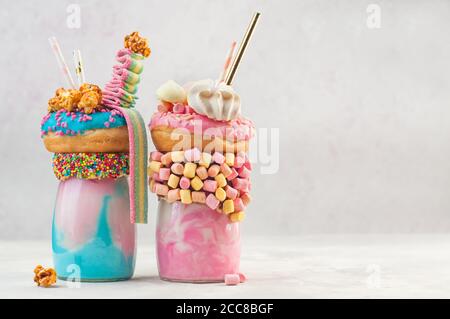 Zwei Freak-Shakes mit Donut und Baisern über Grau Hintergrund mit Kopierbereich Stockfoto